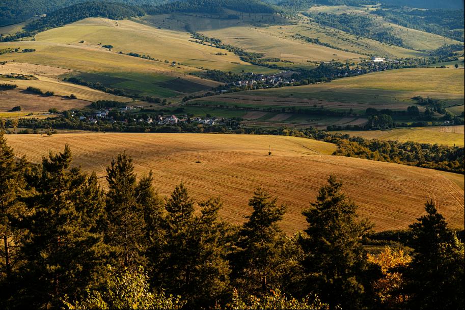 Panoramic view of Lower Tatra mountains – rolling hills, golden fields and a village in the valley